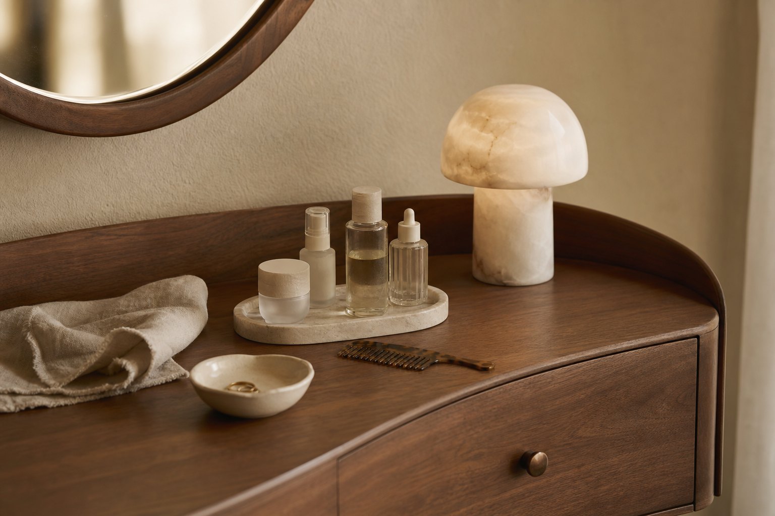 Vanity table still life with walnut table, alabaster lamp, unlabelled skincare bottles, ceramic dish and linen towel