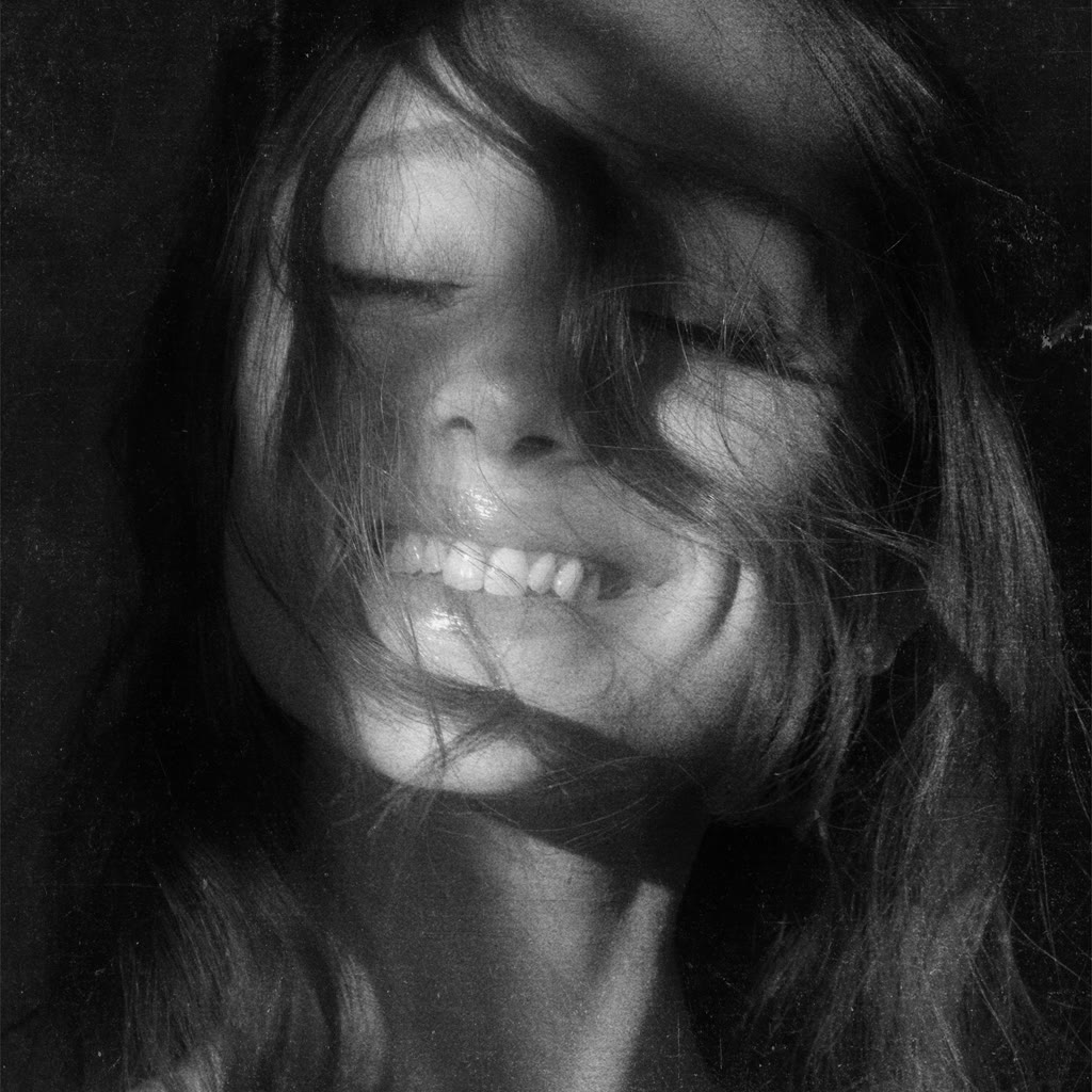 Black-and-white Petal album cover portrait of Ariana Grande smiling behind loose hair