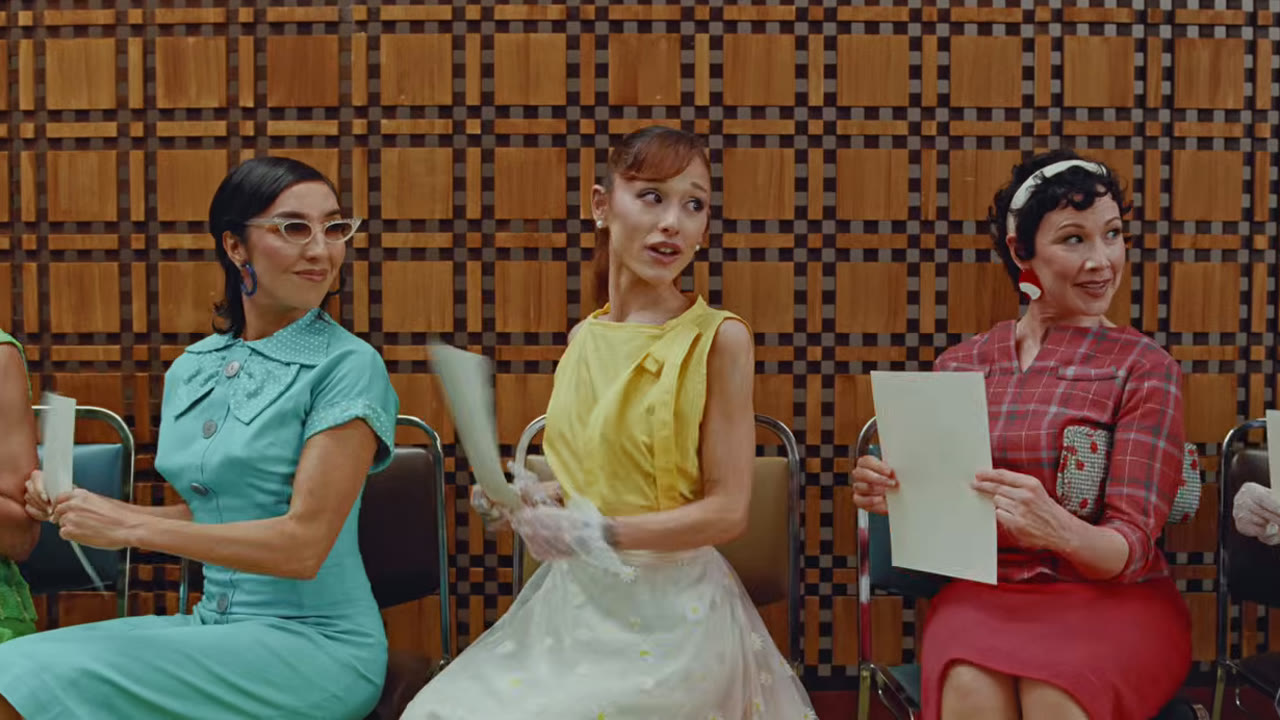 Ariana Grande as Pepper seated among colour-coordinated audition candidates in the Petal music video