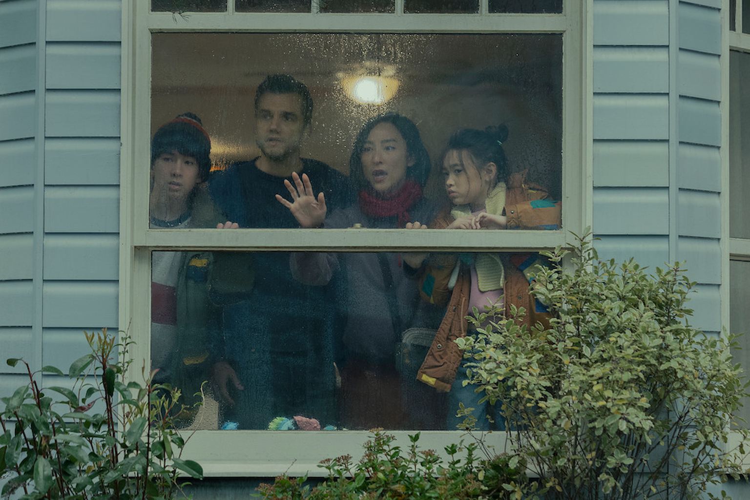 The Delgado family looks through a rain-covered window in Netflix's The Last House