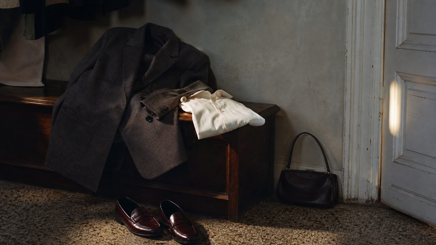 Tailored blazer, ivory shirt, oxblood loafers and a dark leather bag in a lived-in dressing room