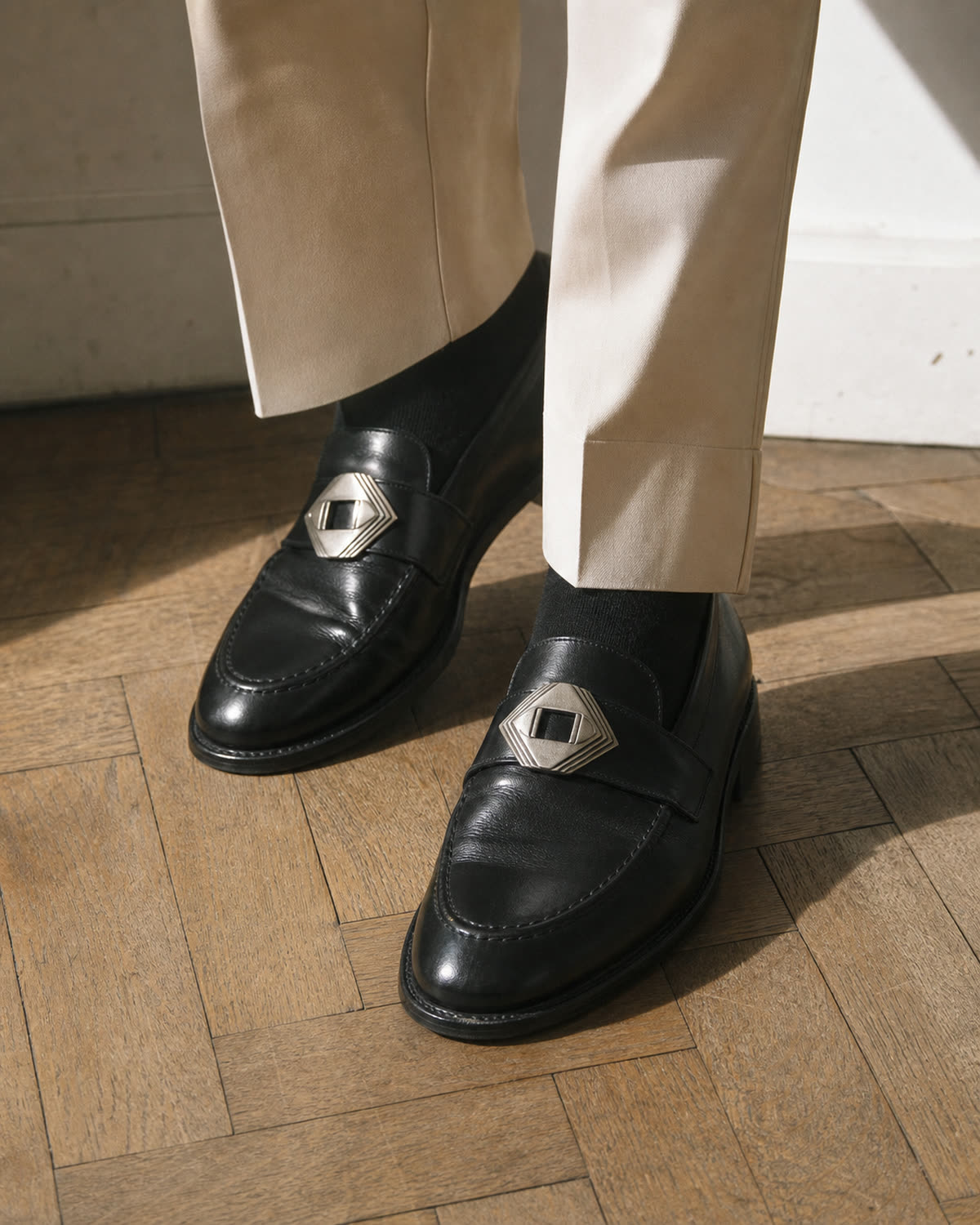 Removable antique-silver geometric shoe clips attached to black leather loafers