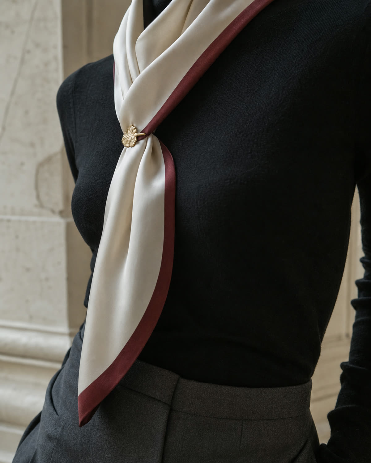 Lightweight antique-gold leaf brooch securing a cream silk scarf with an oxblood border
