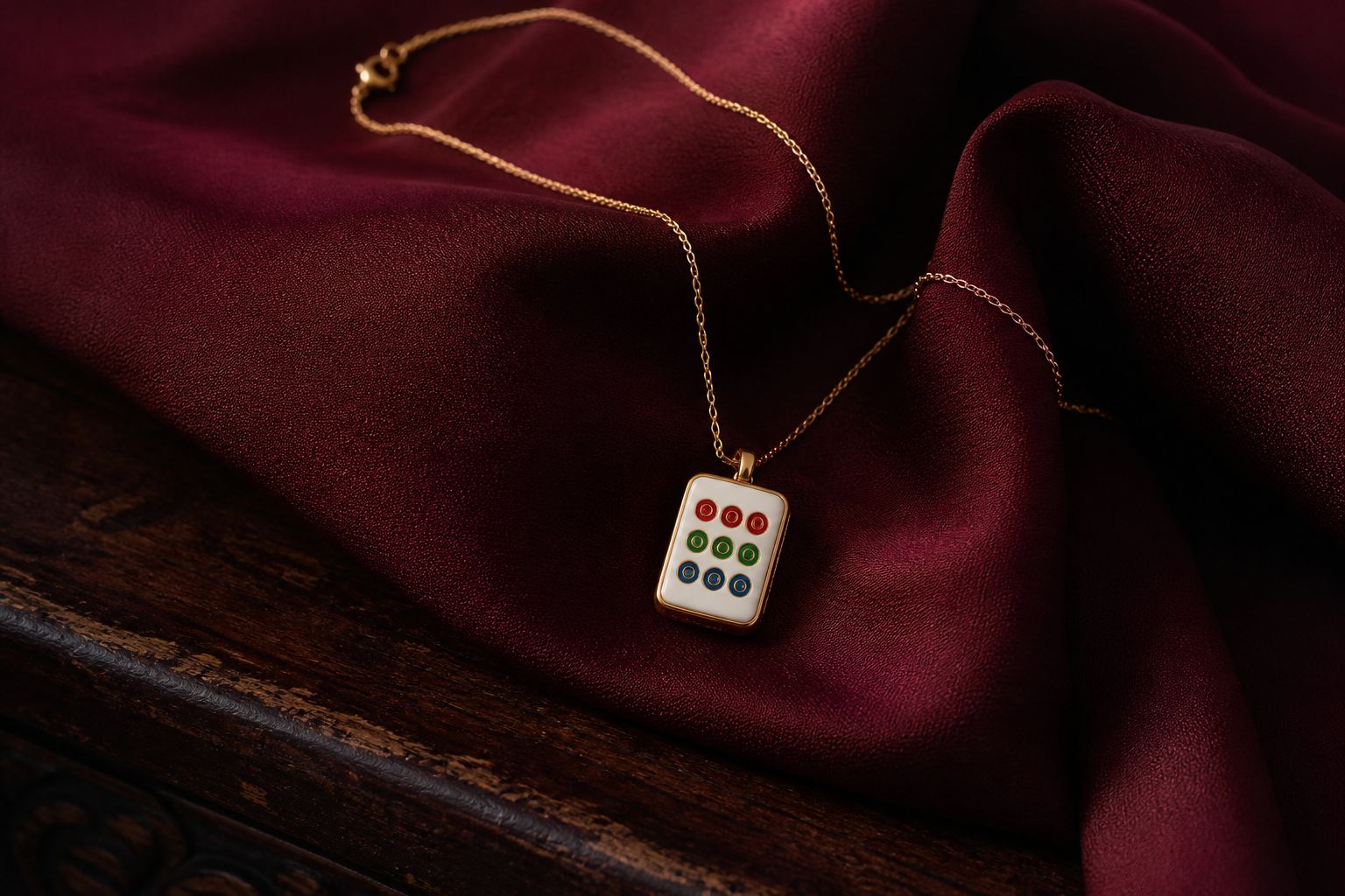 Gold chain with an ivory nine-circle mahjong tile pendant arranged on oxblood silk