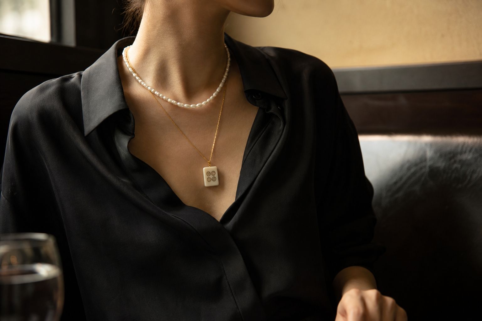Black silk blouse styled with a pearl strand, fine gold chain and small four-circle mahjong tile pendant