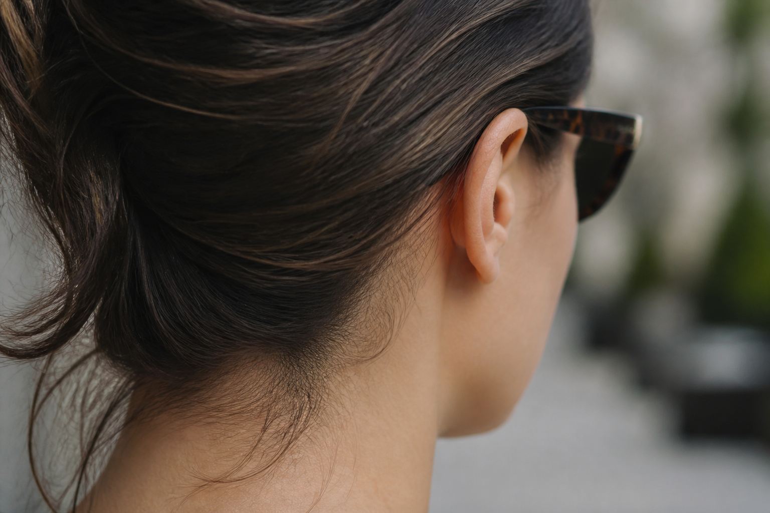 Rear close-up showing a tortoiseshell sunglasses temple resting level above the ear with the face outside the frame