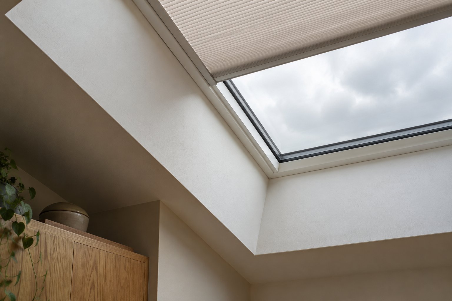 Close view of a rooflight reveal with a partially drawn fitted pleated shade